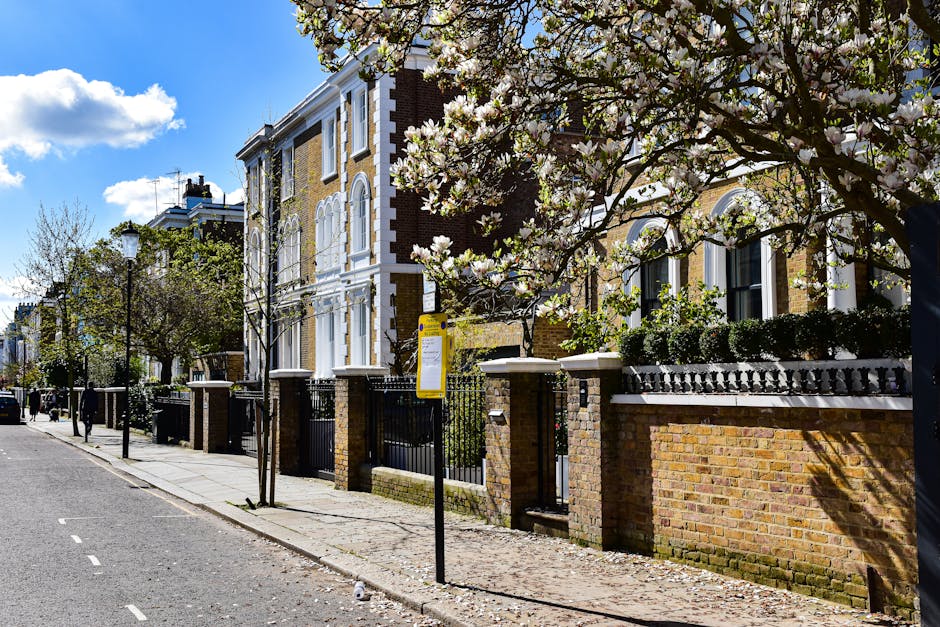 A close-up view of a brick residential building on Melbourne Terrace with two white-framed windows on the upper floor, one of which is slightly open, and two arched entrances at street level, one with